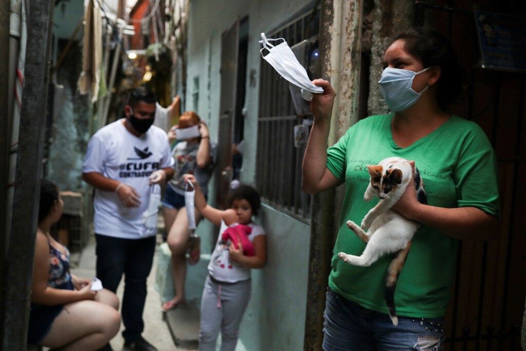 Una mujer agita una máscara facial protectora dada por miembros de la Central Unica das Favelas (CUFA), una organización no gubernamental brasileña, en medio del brote de la enfermedad coronavirus (COVID-19) en la favela de Heliópolis en Sao Paulo, Brasil, el 18 de junio de 2020.