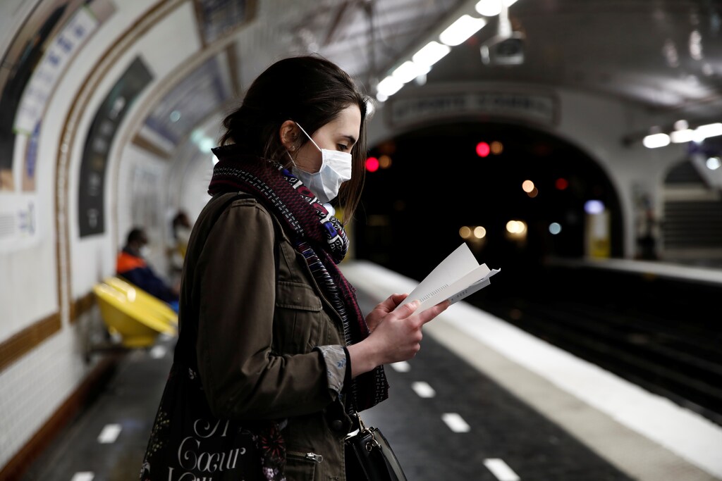 A woman wearing a protective face mask reads a book on a platform at a metro station of Paris transport network (RATP) during the outbreak of the coronavirus disease (COVID-19) in Paris, France, May 5, 2020. REUTERS/Benoit Tessier - RC2EIG9NNACY