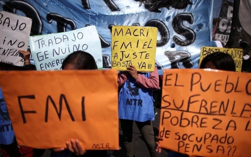 People hold placards as they attend a demonstration against economic measures of Argentine President Mauricio Macri's government, in Buenos Aires, Argentina September 24, 2019. The placards read: "IMF","IMF the adjustment", "The people suffer poverty", "Enough" and "Genuine work". REUTERS/Agustin Marcarian - RC118FBA70B0