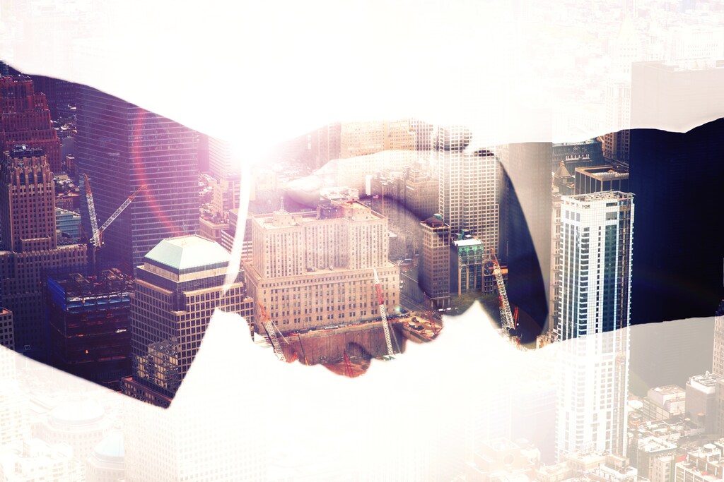 Multiple exposure shot of businesspeople shaking hands superimposed against a city background; trust at work, use of AI