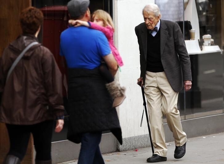 A man walking with the help of a cane passes a family on a street in London October 18, 2013. Britain's Health Secretary Jeremy Hunt said in a speech at the National Children and Adults Services (NCAS) conference on Friday that it is a national shame that "there are 800,000 people in England who are chronically lonely", quoting the Campaign to End Loneliness for the figure, according to local media. REUTERS/Luke MacGregor (BRITAIN - Tags: SOCIETY HEALTH)