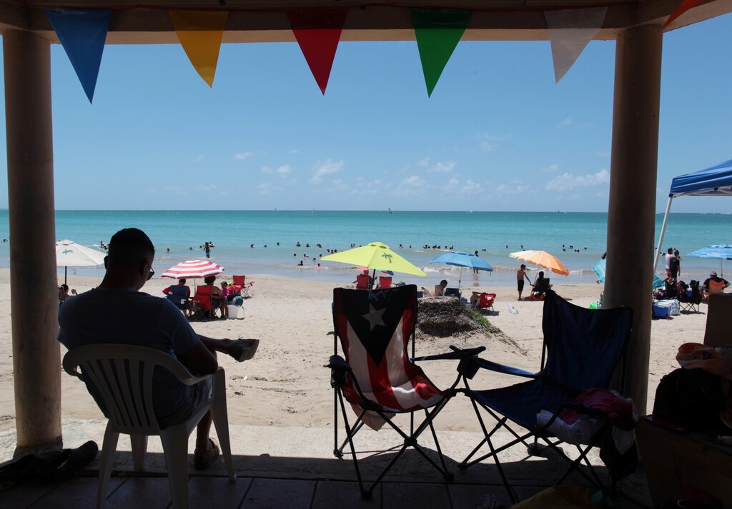 People enjoy a day at the beach as the economically struggling U.S. island territory of Puerto Rico voted overwhelmingly on Sunday in favour of becoming the 51st state, in San Juan, Puerto Rico June 11, 2017. REUTERS/Alvin Baez - RTS16MQX