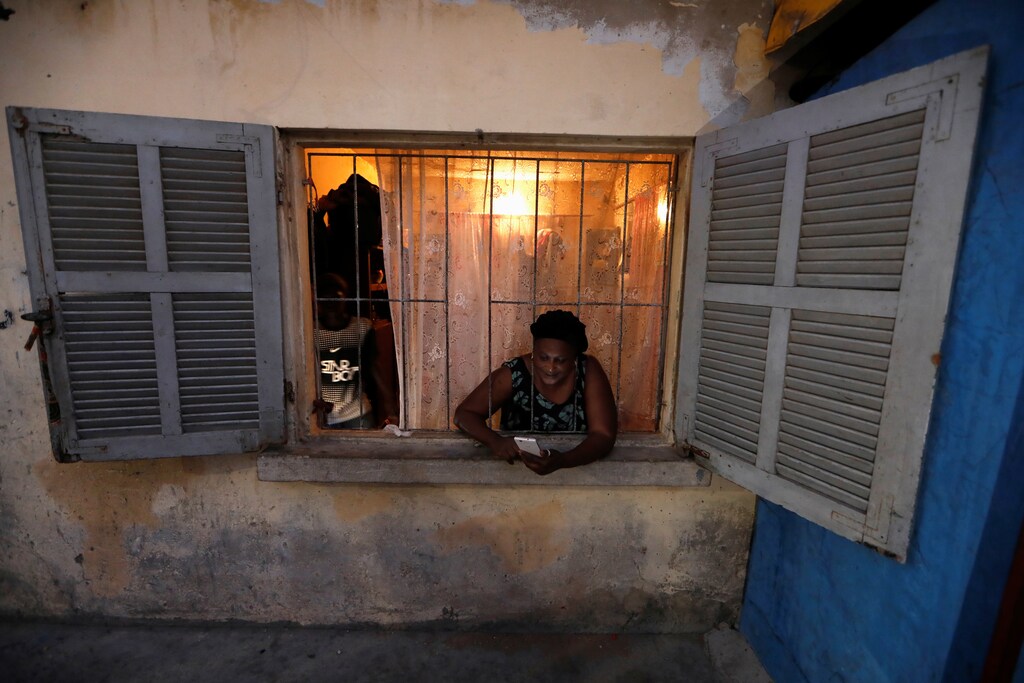 A woman uses her mobile phone as she stands at her home window before a curfew, amid the spread of the coronavirus disease (COVID-19) in Pikine suburb of Dakar, Senegal April 22, 2020