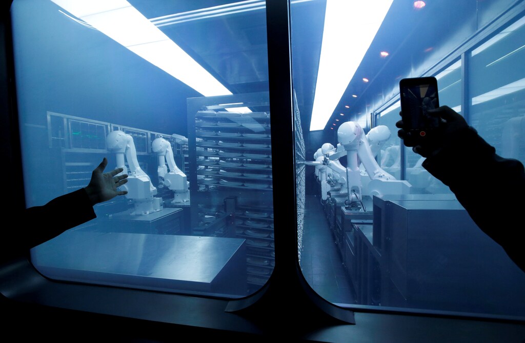 A customer takes a picture as robotic arms collect pre-packaged dishes from a cold storage, done according to the diners' orders, at Haidilao's new artificial intelligence hotpot restaurant in Beijing, China, November 14, 2018. Picture taken November 14, 2018. REUTERS/Jason Lee TPX IMAGES OF THE DAY - RC14D8976800
