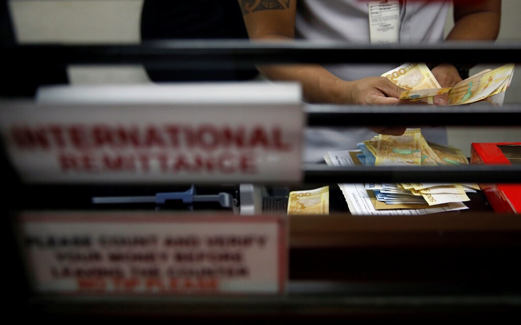 A teller counts Philippine peso bills at an international money remittance center in Makati City, Metro Manila, Philippines September 19, 2018