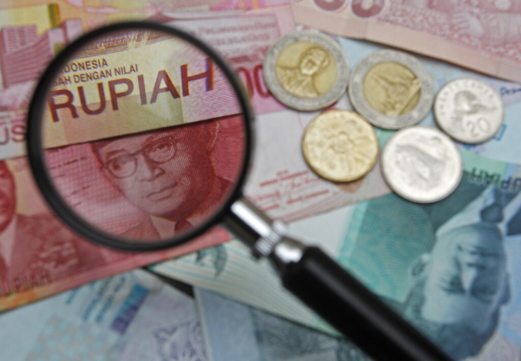 A 100,000 Indonesian rupiah note is seen through a magnifying glass among other Southeast Asian currency note in this photo illustration taken in Singapore March 14, 2013. Singapore's foreign exchange market has come under pressure for change since regulators, spurred by a global scandal over bankers rigging key lending rates, ordered reviews last autumn into various rates set by the city-state's banking association. The probes uncovered attempts by traders to manipulate Singapore's rate fixings for certain currencies, fuelling the ire of central bankers in Malaysia and Indonesia who for years have held concerns about the impact of offshore speculation on their own spot currency markets. REUTERS/Edgar Su (SINGAPORE - Tags: BUSINESS) - GM1E93F0EW301