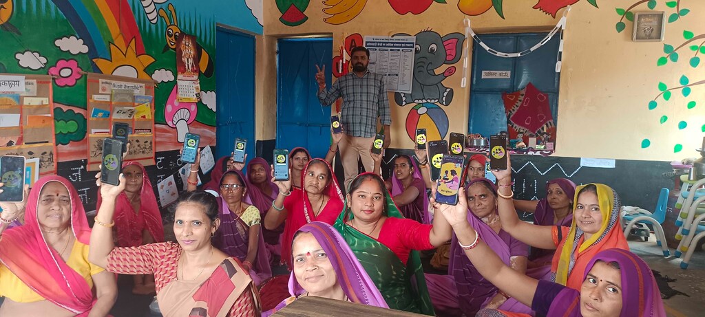 A group of emaployees of an Anganwadi daycare centre in rural India hold up their smartphones during a digital literacy training course.