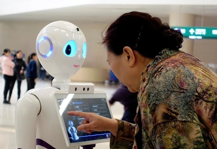 A woman touches a screen on a robot developed by iFlytek at the outpatient hall of People's Liberation Army General Hospital in Beijing, China March 16, 2017. Picture taken March 16, 2017. Zhao Naiming/via REUTERS