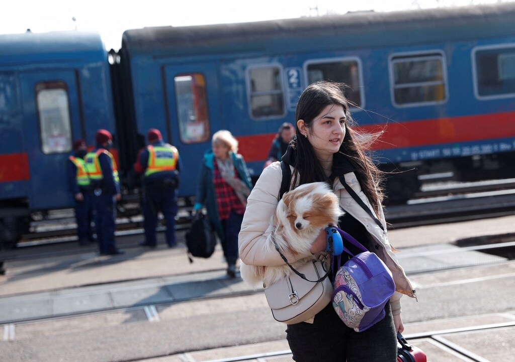 A woman holds a dog as she arrives at the train station in Zahony, after fleeing Russia's invasion of Ukraine, Hungary March 4, 2022. REUTERS/Bernadett Szabo
