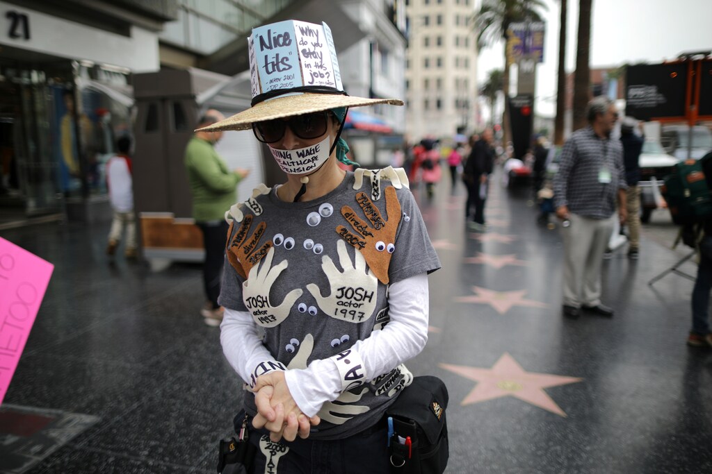 A woman wears an outfit with the names of all the men in Hollywood who sexually harassed her, during a #MeToo protest march in LA, November 2017.