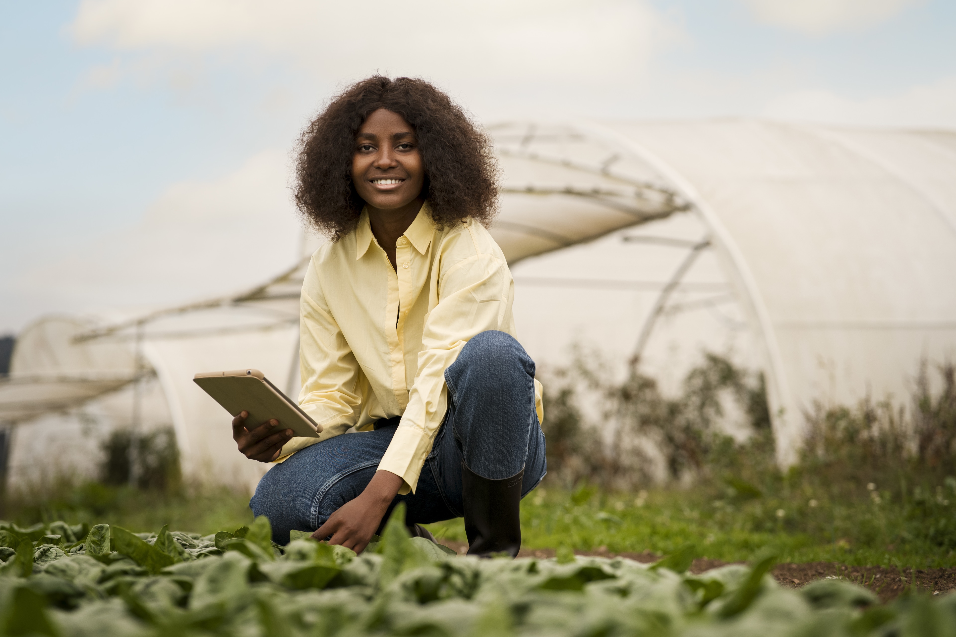 Food crisis: Young woman holding ipad in front of an agricultural facility.