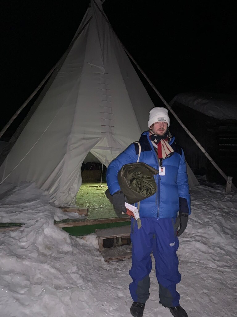 Clutching his Swiss army issue sleeping bag, Andrew Funk stands in front of the teepee he's called home for Davos