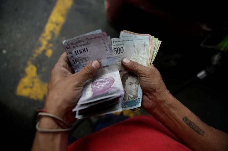 A worker counts Venezuelan bolivar notes at a gas station of Venezuelan state oil company PDVSA in Caracas, Venezuela December 1, 2017. REUTERS/Marco Bello