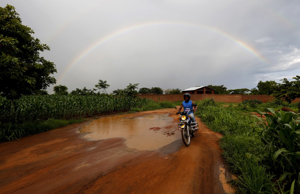 Storm clouds hang over a rainbow as a motorcyclist rides past a field of maize after late rains near Malawi's capital Lilongwe, February 1, 2016. Late rains in Malawi threaten the staple maize crop and have pushed prices to record highs. About 14 million people face hunger in Southern Africa because of a drought that has been exacerbated by an El Nino weather pattern, according to the United Nations World Food Programme (WFP). REUTERS/Mike Hutchings TPX IMAGES OF THE DAY - GF10000292435