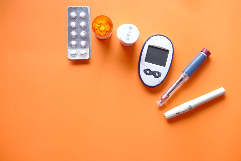 Insulin pen, diabetic measurement tools and pills on orange background