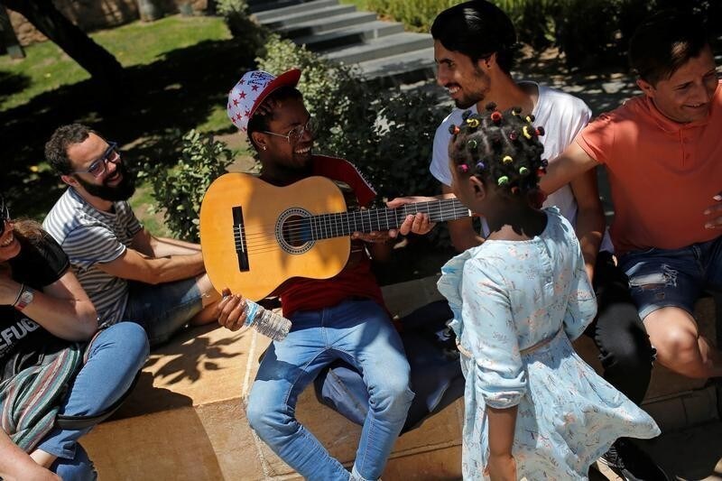Refugees hold a guitar during a social action in which refugees and citizens look at each other in silence to mark the World Refugee Day, organized by the Spanish Commission for Refugee Aid (CEAR) in Malaga, Spain, June 20, 2018.