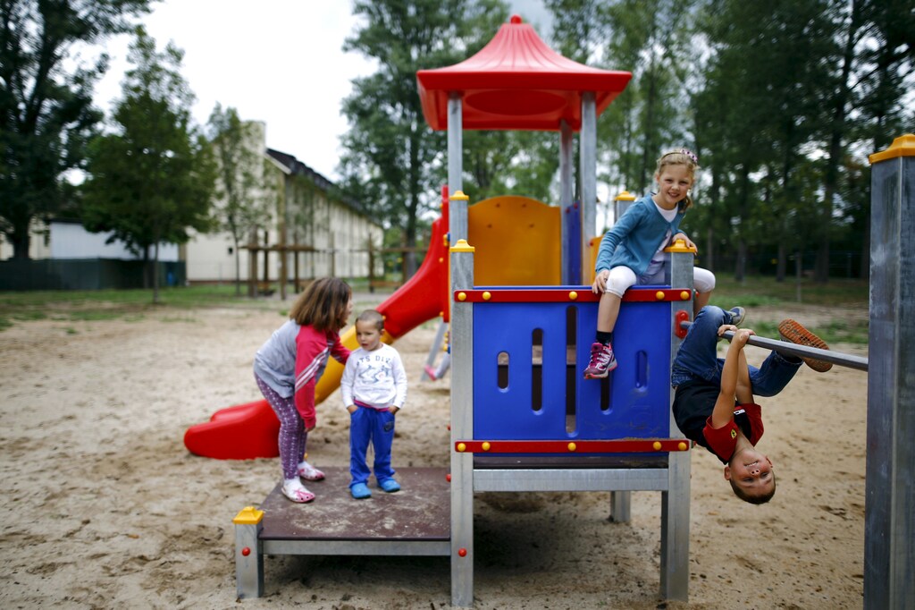 Four-year old Tom (R) and his six-year old sister Lisa from Offenbach show Serbian refugee Dragan (2nd L) and his sister Tamara (L) how to play on the climbing frame at a refugee camp in Hanau, Germany, August 18, 2015. Tom and Lisa learned from her mother that a lot of refugees come to Germany and most of them, especially the children, don't have much clothes or toys to play with. The two German youngsters than decided to visit the refugee camp to donate from their own wardrobe and toys and "make friends" with the kids from abroad. REUTERS/Kai Pfaffenbach - RTX1ONYJ