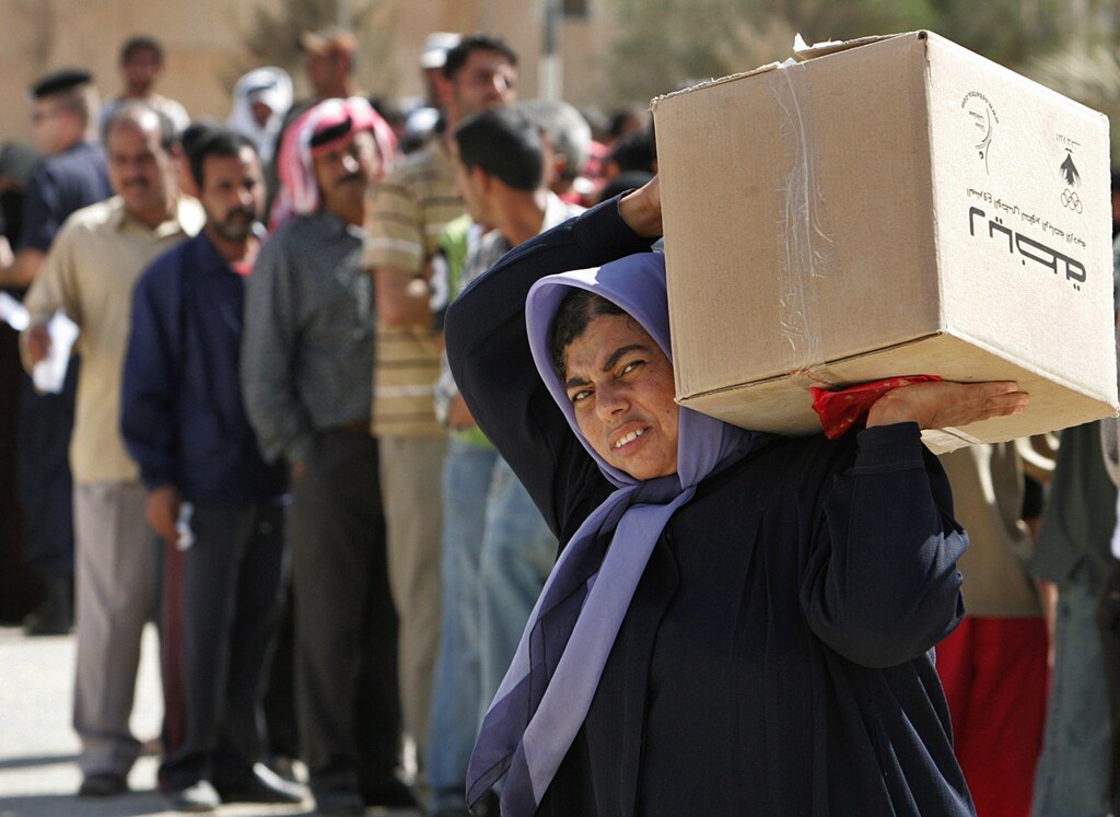 A woman carries a parcel of food donated by a Jordanian charity, "Tikyet Um Ali", in the northern Jordanian city of Irbid October 15, 2006. Moslem charities alongside government sponsored funds compete to get donations during Ramadan from wealthy Muslims seeking God's mercy by giving part of their income to the poor. To match feature JORDAN-ZAKAT Picture taken October 15, 2006. REUTERS/Muhammad Hamed (JORDAN) - GF1DTTTILJAA