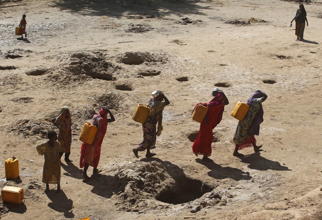 Women carry jerry cans of water from shallow wells dug from the sand along the Shabelle River bed, which is dry due to drought in Somalia's Shabelle region, March 19, 2016. REUTERS/Feisal Omar TPX IMAGES OF THE DAY - GF10000351737