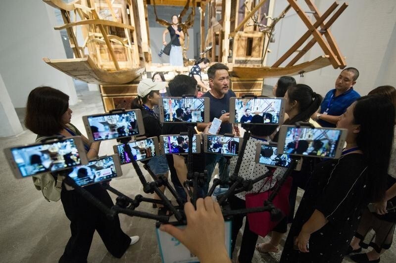 A reporter holds ten smartphones while doing live broadcasting on different platforms from the first Sculpture Projects Pingyao art festival in Jinzhong, Shanxi province, China July 19, 2018 Picture taken July 19, 2018.