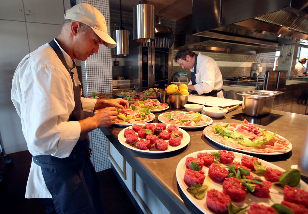A staff member prepares cured meat dishes at the Eataly motorway restaurant on a highway in Modena, central Italy, May 30, 2016. REUTERS/Stefano Rellandini - RTX2EVFZ