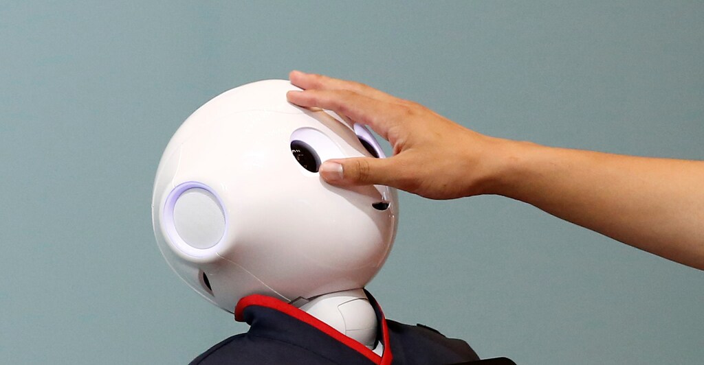 A man touches the head of a SoftBank humanoid robot known as Pepper at the venue for Pepper World 2016 Summer, ahead of its opening on Thursday, in Tokyo, Japan, July 20, 2016.