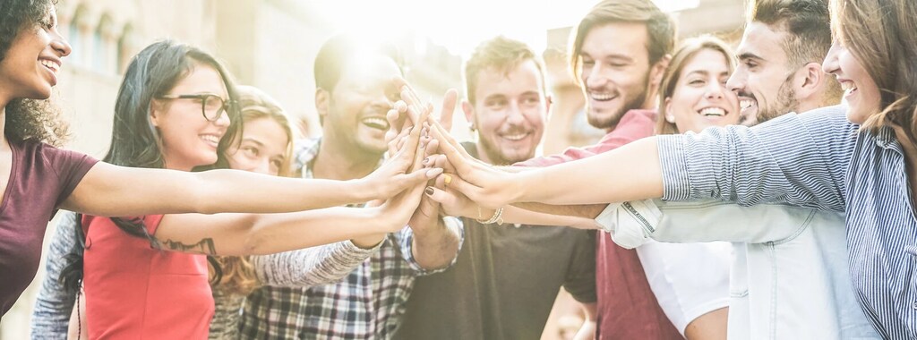 Un grupo de jóvenes se dan la mano. Establecer vínculos entre culturas puede contribuir a reforzar la felicidad y la salud mental.