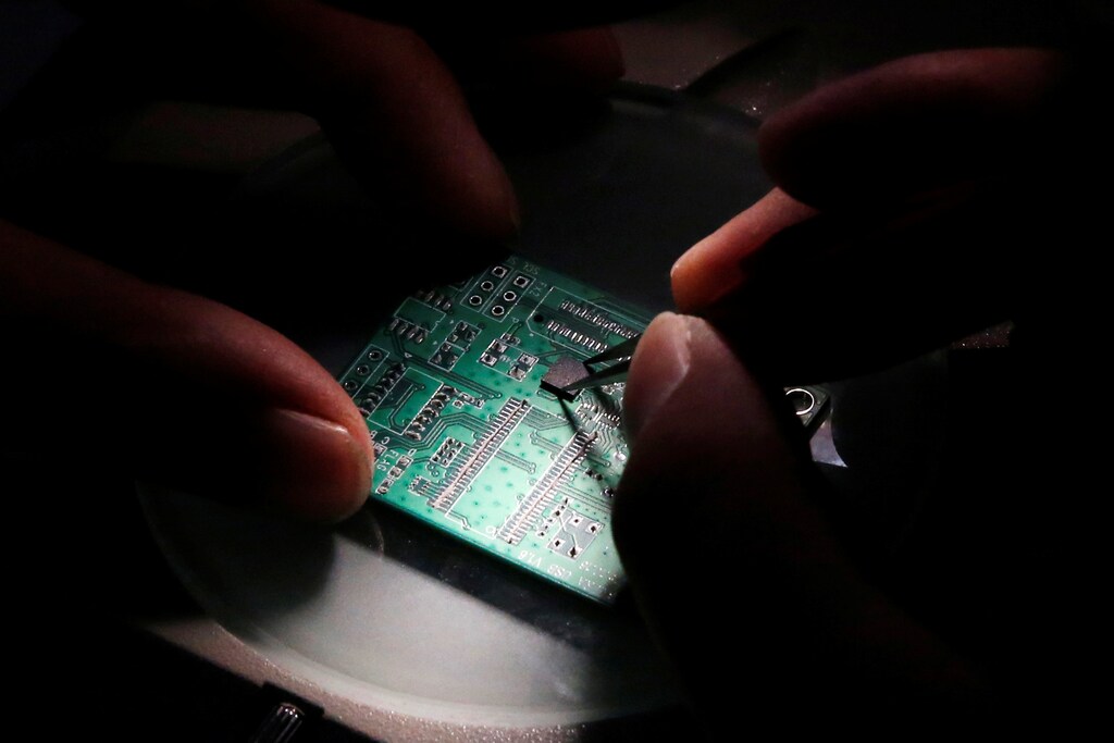 A researcher plants a semiconductor on an interface board which is placed under a microscope during a research work to design and develop a semiconductor product at Tsinghua Unigroup research centre in Beijing, China, February 29, 2016. REUTERS/Kim Kyung-Hoon - D1AETETTRBAA