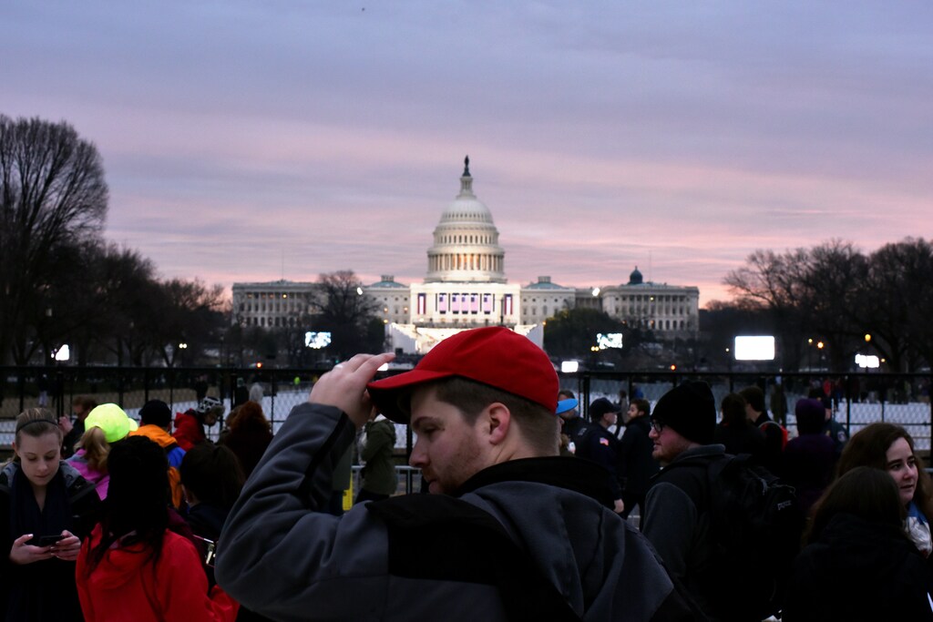 A supporter of U.S. President-elect Donald Trump adjusts his red baseball cap as the sun rises over the U.S. Capitol on the National Mall before Trump is to be sworn in in Washington, U.S., January 20, 2017. REUTERS/James Lawler Duggan - RTSWGOI
