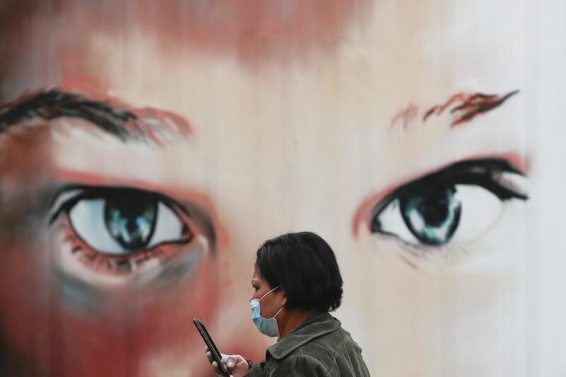 A woman wearing a protective mask and gloves walks outside a hospital during the partial lockdown as part of a 15-day state of emergency following the coronavirus disease outbreak in Madrid, Spain March 17, 2020. REUTERS/Susana Vera - RC2NLF97NATC