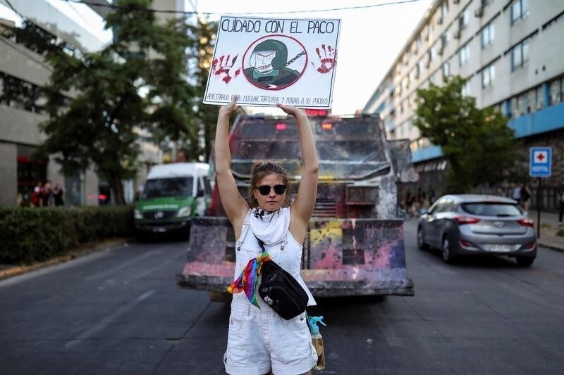 A demonstrator holds up a sign in front of a riot police vehicle during a protest against Chile's government, at Providencia, a wealthy neighbourhood, in Santiago, Chile December 3, 2019. The sign reads: "Be careful with the policeman; trained to maim, torture and kill his people". REUTERS/Pablo Sanhueza - RC2ZND9PJPR0