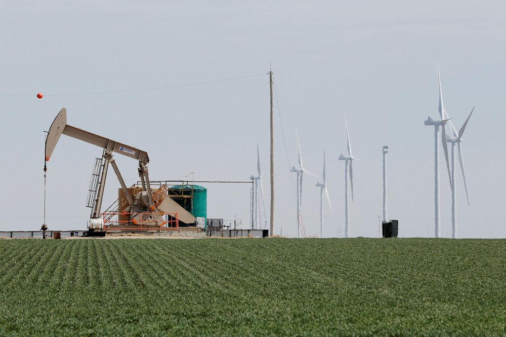 An oil derrick and wind turbines stand above the plains north of Amarillo, Texas, U.S., March 14, 2017