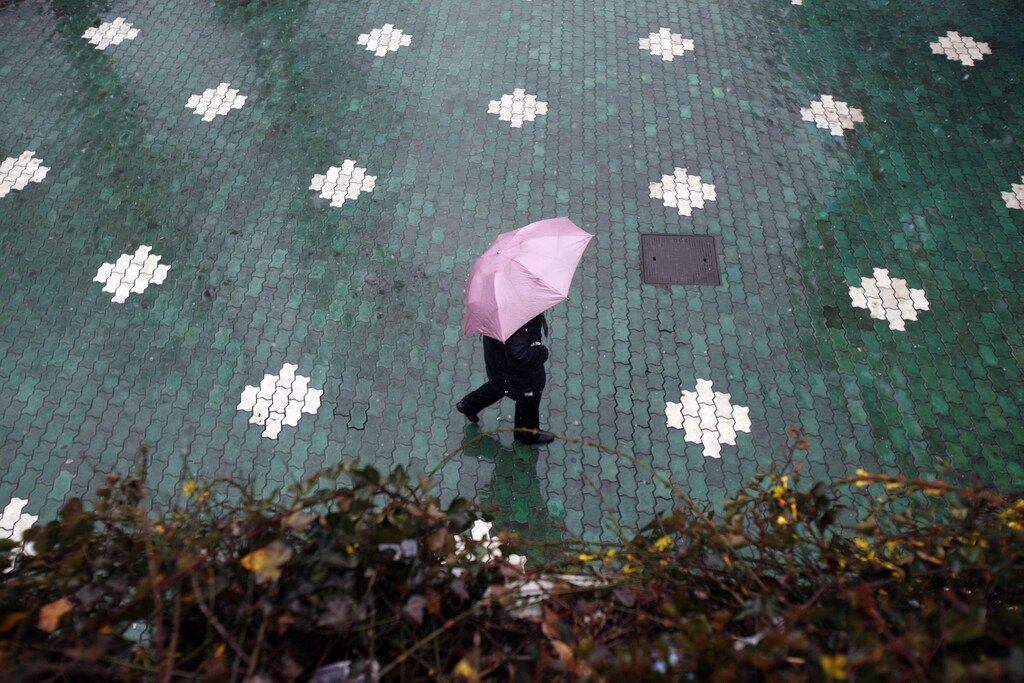 A man walks near the Huangpu River as snow falls in downtown Shanghai January 26, 2008. Heavy snow and rain closed airports, highways and train lines across central and eastern China on Saturday, stranding tens of thousands of travellers and threatening to block food supplies. REUTERS/ Nir Elias (CHINA) - GM1DXCXXMUAA