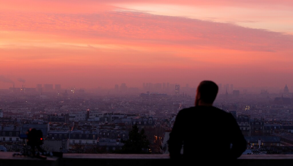 A tourist looks at the sun rises as small-particle haze hangs above the skyline in Paris, France, December 9, 2016 as the City of Light experienced the worst air pollution in a decade. REUTERS/Gonzalo Fuentes - RTSVCYN