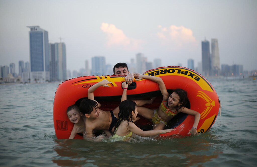 A man plays with his family at Mamzar beach in Dubai October 25, 2013.