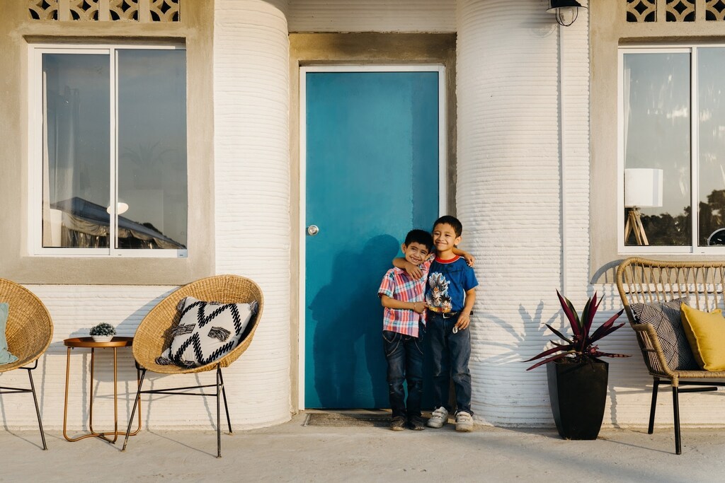 children in front of a 3D-printed home in Mexico