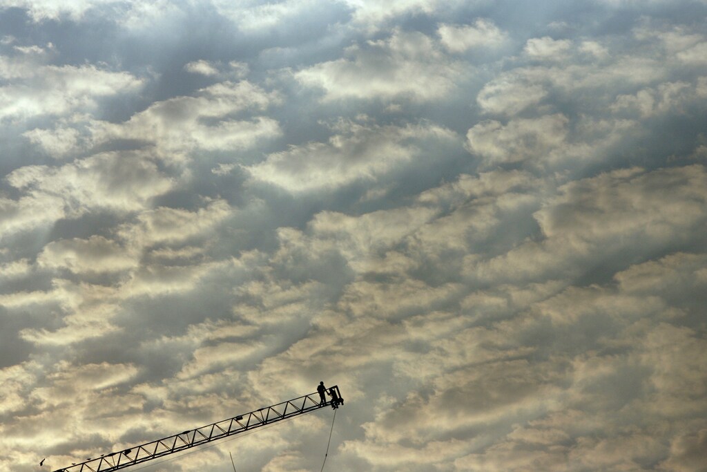Labourers work on the edge of a ladder during the construction of a building in Mumbai March 20, 2007. Surging demand for homes and offices in an economy forecast to grow 9.2 percent in this fiscal year had triggered a spate of listing plans by developers, but rising interest rates, steep valuations, lack of earnings, a market sell-off and the poor performance of recent issues have made investors edgy. REUTERS/Arko Datta (INDIA) - GM1DUVYSAMAA