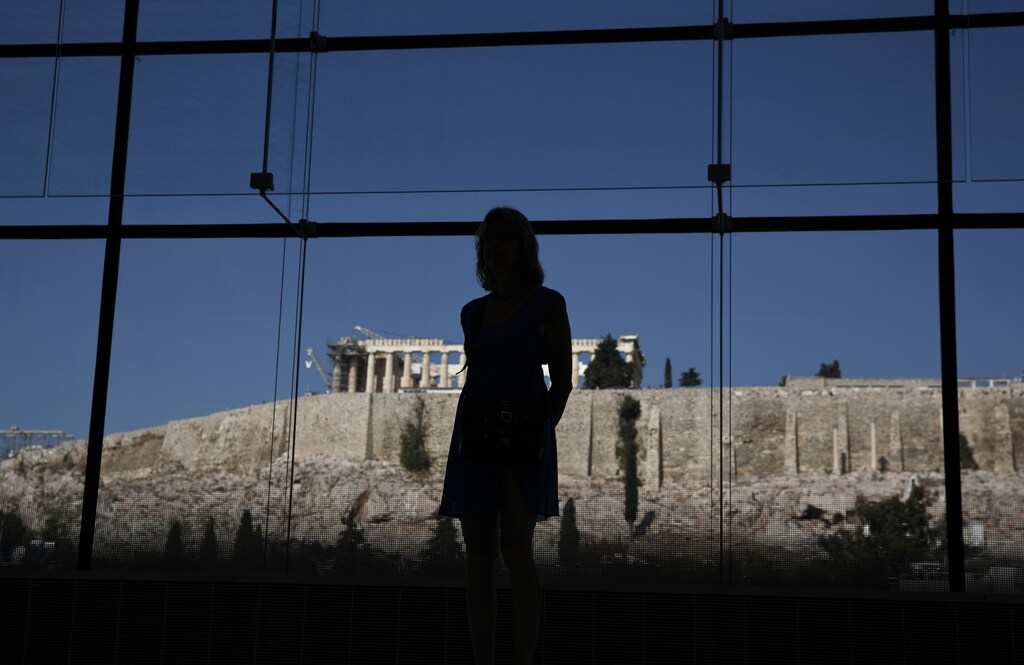 A woman looks at exhibits on display in the Parthenon hall at the Acropolis museum, as the temple of the Parthenon is seen in the background, in Athens October 10, 2014. Human rights lawyer Amal Alamuddin Clooney, fresh from her marriage to Hollywood heart-throb George Clooney last month, is heading to Athens to advise the Greek government in its battle to repatriate the ancient Elgin Marbles statues from Britain. The Marbles are a set of ancient Greek sculptures taken to London after being removed from the Acropolis in Athens by a British aristocrat, Lord Elgin, while Athens was under Ottoman control in the 19th Century. Greece has sought their return from the British Museum for decades, to no avail. REUTERS/Yorgos Karahalis (GREECE - Tags: POLITICS SOCIETY TRAVEL ENTERTAINMENT) - RTR49O0A
