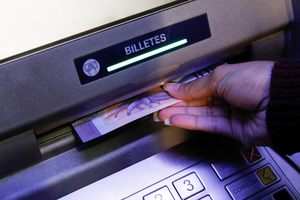 A woman takes the new Bolivar Soberano (Sovereign Bolivar) bills, as she withdraws cash from an automated teller machine (ATM) at the Banesco bank headquarters in Caracas, Venezuela August 20, 2018. REUTERS/Carlos Garcia Rawlins - RC1C29CF3DC0