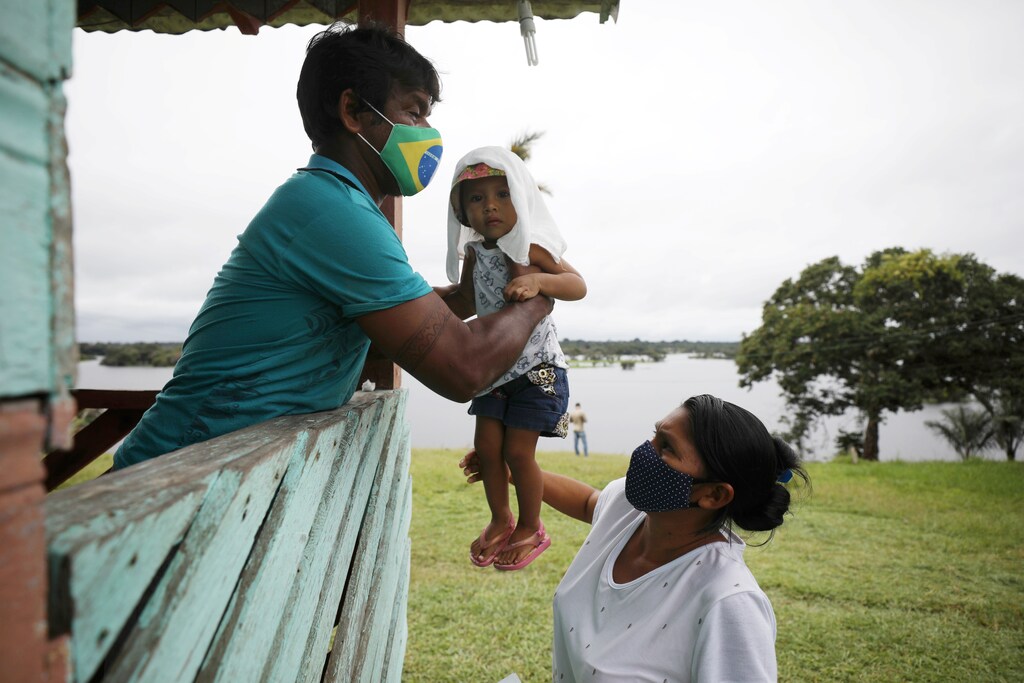 An Indigenous man holds a baby before receiving a dose of Sinovac's CoronaVac coronavirus disease (COVID-19) vaccine at Sao Jose Village in the Indigenous land Rio Urubu from the ethnicity Mura in the Urubu river banks in Itacoatiara, Amazonas state, Brazil, February 13, 2021. Picture taken February 13, 2021.