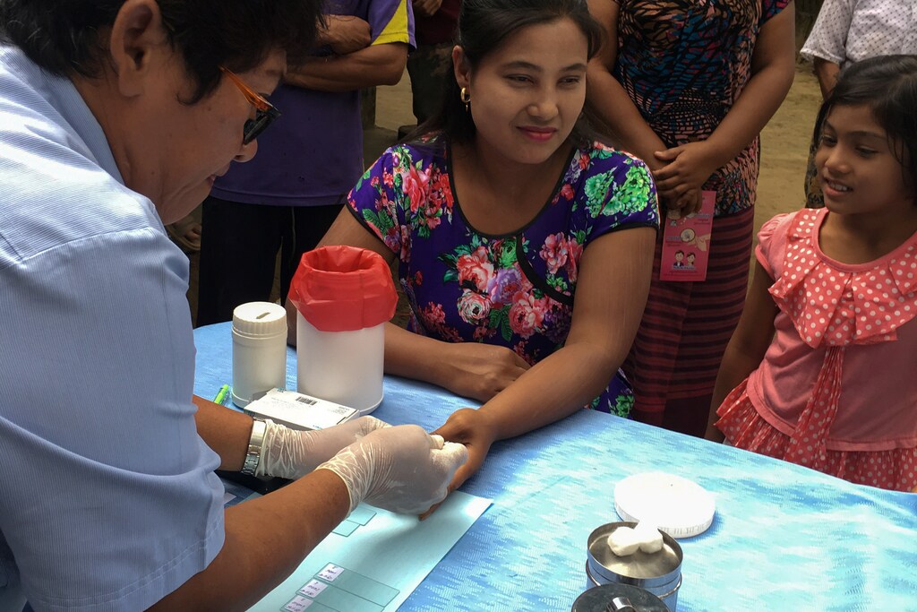 A public health worker takes a blood sample from a woman to be tested for malaria in Thailand
