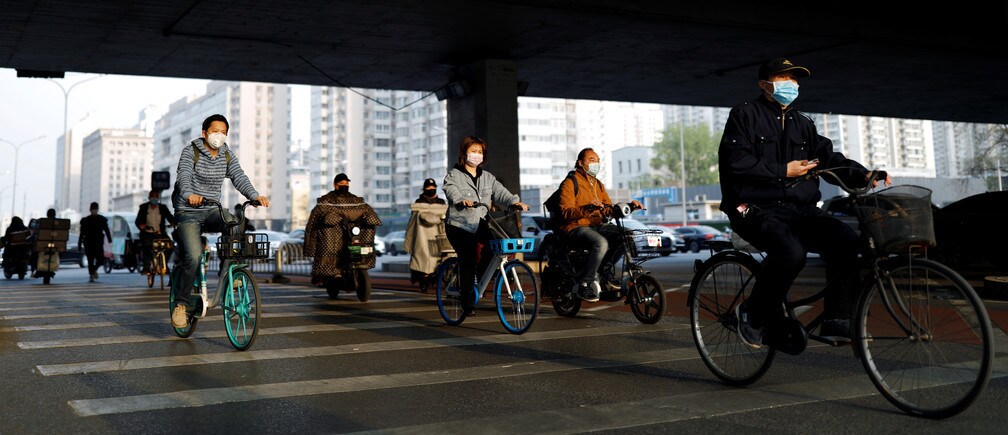 People wearing protective face masks ride bicycles and scooters on a street, following an outbreak of the coronavirus disease (COVID-19), in Beijing, China April 7, 2020. REUTERS/Carlos Garcia Rawlins - RC2MZF9BMYYS
