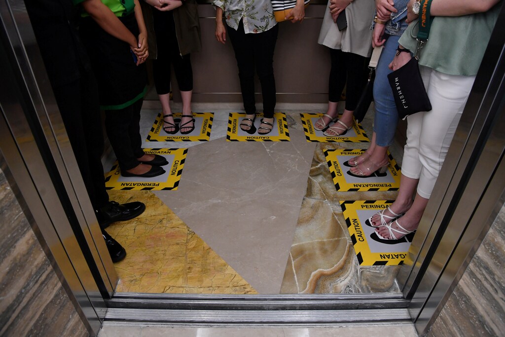Visitors stand inside boxes for social distancing inside an elevator at a shopping mall amid the spread of coronavirus disease (COVID-19) in Surabaya, East Java province, Indonesia, March 18, 2020 in this photo taken by Antara Foto. Antara Foto/Zabur Karuru/ via REUTERS ATTENTION EDITORS - THIS IMAGE WAS PROVIDED BY A THIRD PARTY. MANDATORY CREDIT. INDONESIA OUT. TPX IMAGES OF THE DAY - RC2CMF9AH704