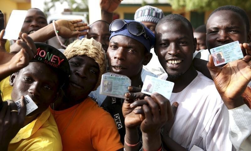 Men holds ID cards as they wait in line to register to vote in a polling station during elections in Kano March 28, 2015. Nigerians vote on Saturday in what looks set to be the first genuine electoral contest since the end of military rule in 1999, one in which an opposition aspirant has a fighting chance of unseating the incumbent President Goodluck Jonathan. REUTERS/Goran Tomasevic - RTR4V8E1