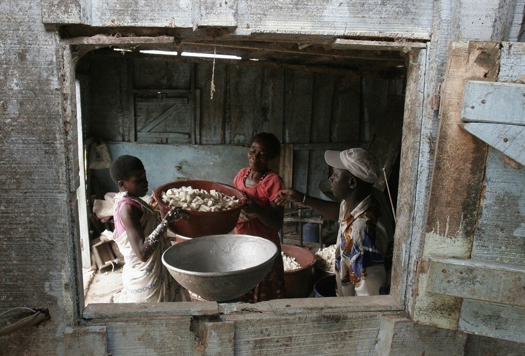 People prepare to grind cassava roots in Bingerville, near Abidjan, June 24, 2008. REUTERS/ Thierry Gouegnon (IVORY COAST) - RTX7A3V