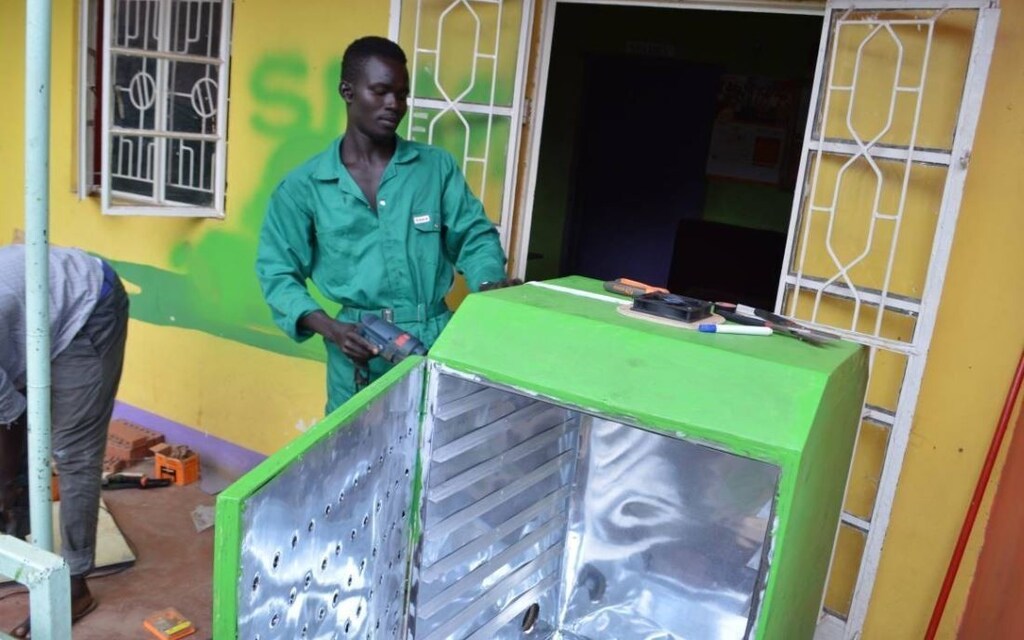 Lawrence Okettayot and Morris Opiyo work on a 'sparky' food dryer at their workshop in Kampala, Uganda, May 13, 2019. Thomson Reuters Foundation/John Okot
