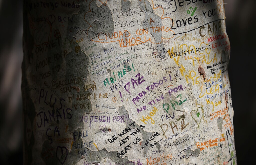 Words and sentences in different languages are written on a tree trunk at an impromptu memorial set up where a van crashed into pedestrians at Las Ramblas in Barcelona, Spain, August 22, 2017. REUTERS/Albert Gea - RC191A2095E0