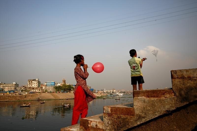 Children enjoy their leisure time with a kite and balloon on the bank of the river Buriganga in Dhaka, Bangladesh, March 12, 2017.