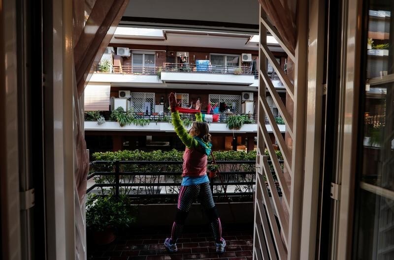 Personal trainer Antonietta Orsini carries out an exercise class for her neighbours from her balcony while Italians cannot leave their homes due to the coronavirus disease (COVID-19) outbreak, in Rome, Italy, March 18, 2020. Picture taken March 18, 2020 REUTERS/Remo Casilli - RC2WMF91LEH7