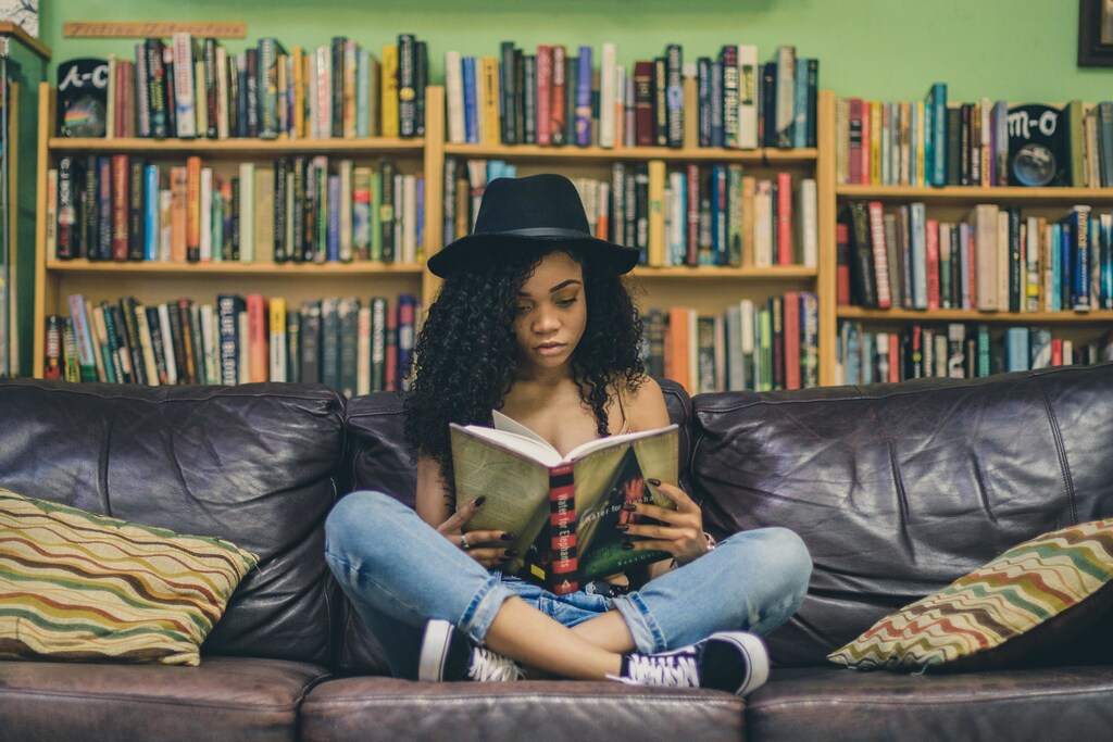 Girl sat on a sofa reading.